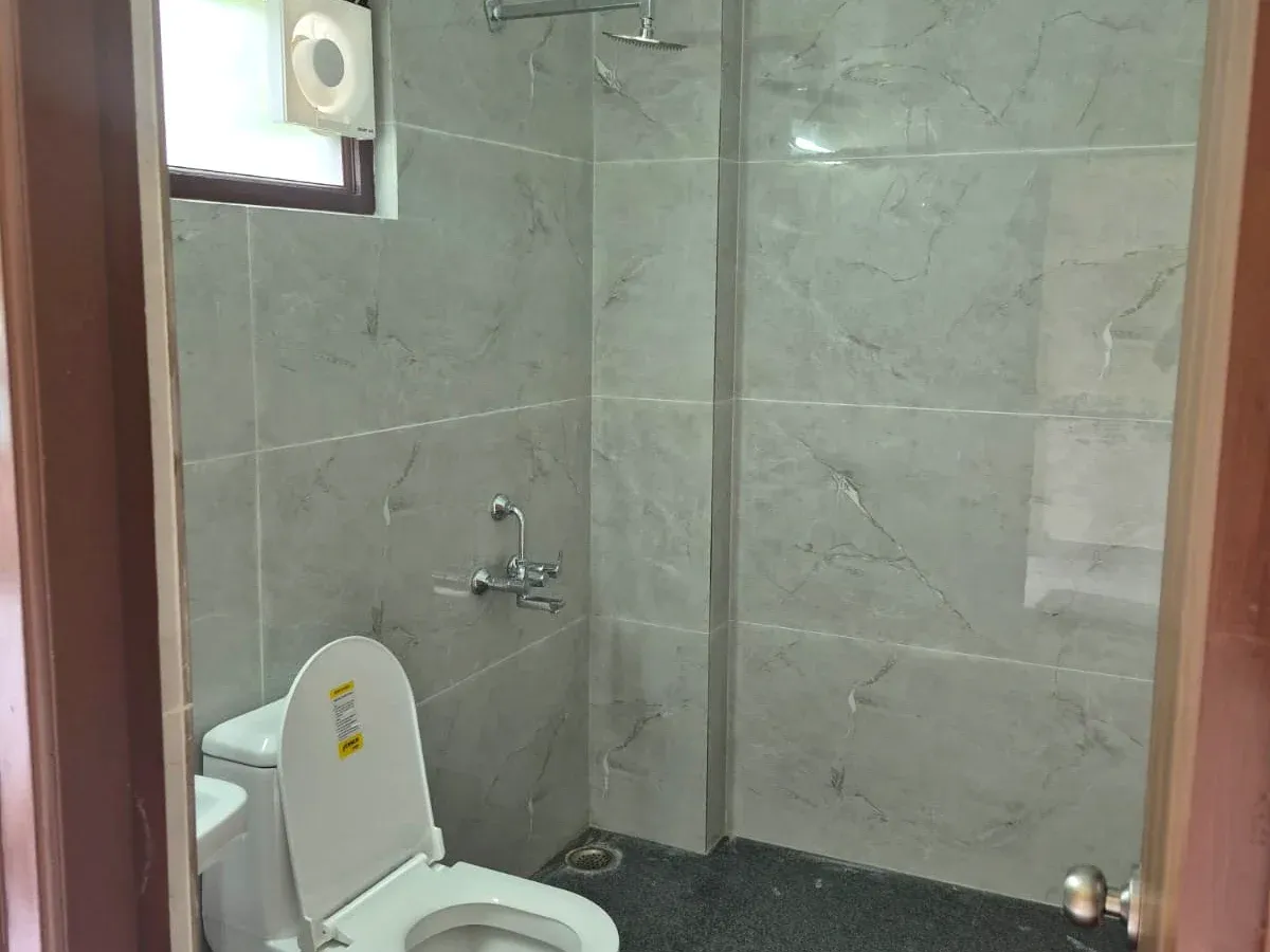 Spacious tiled attached bathroom with rain shower, mixer tap and exhaust fan