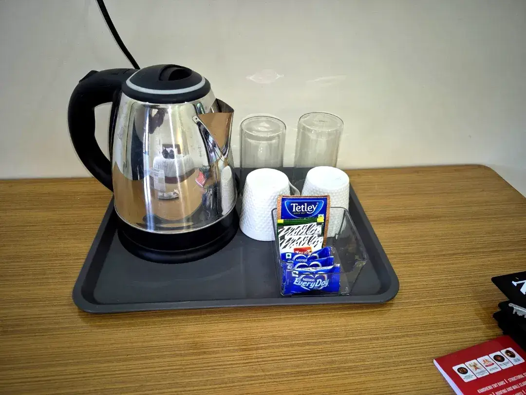 Electric kettle, cups and tea and coffee sachets on a tray